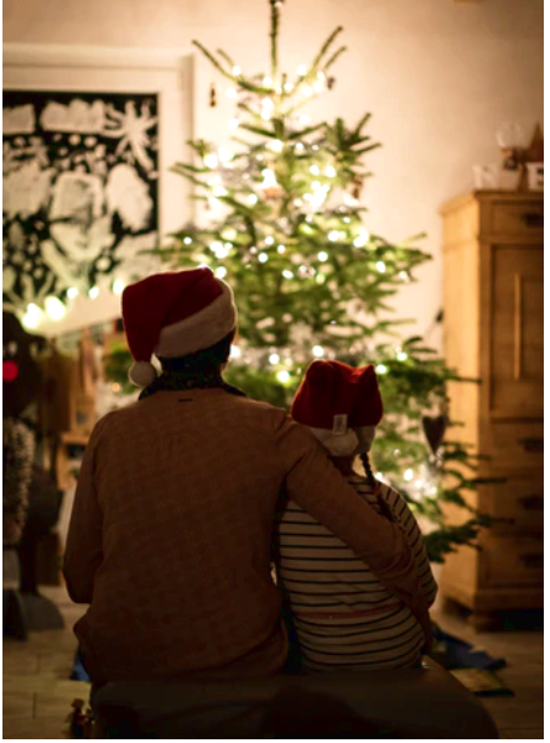 father and child sitting in front of the Christmas tree