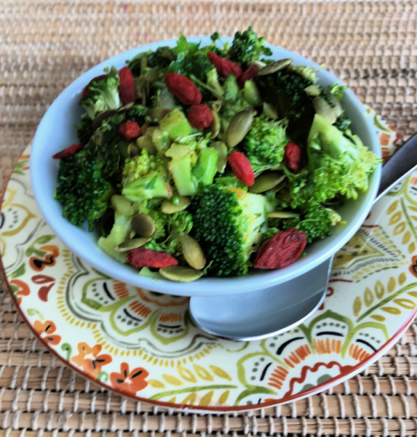 side view of a bowl of raw broccoli salad with goji berries and seeds